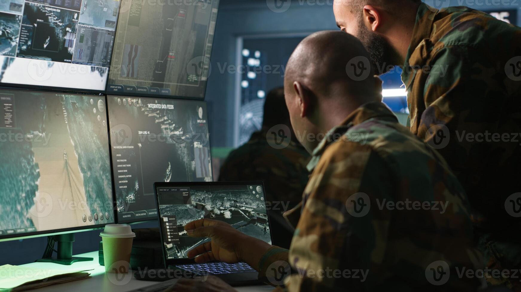 Military soldier in mission control center, overseeing national safety operations using notebook next to colleague. Team of army specialists examining data in monitoring room command center, camera A photo