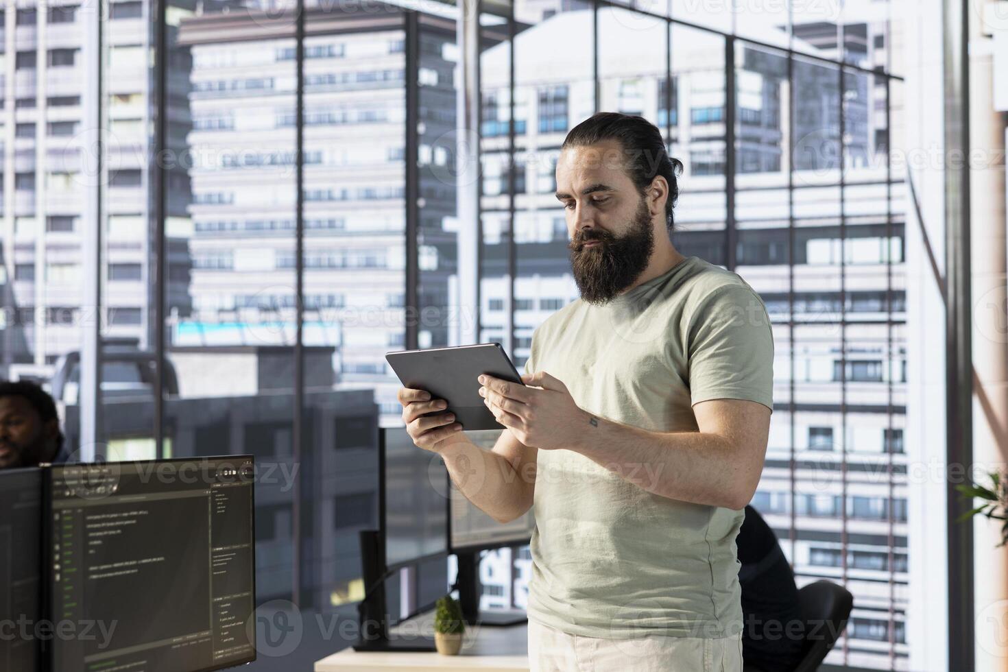 Programmer creating machine learning models that can process and analyze data to improve and automate decision making processes, looking at tablet. Man programming in office using device photo