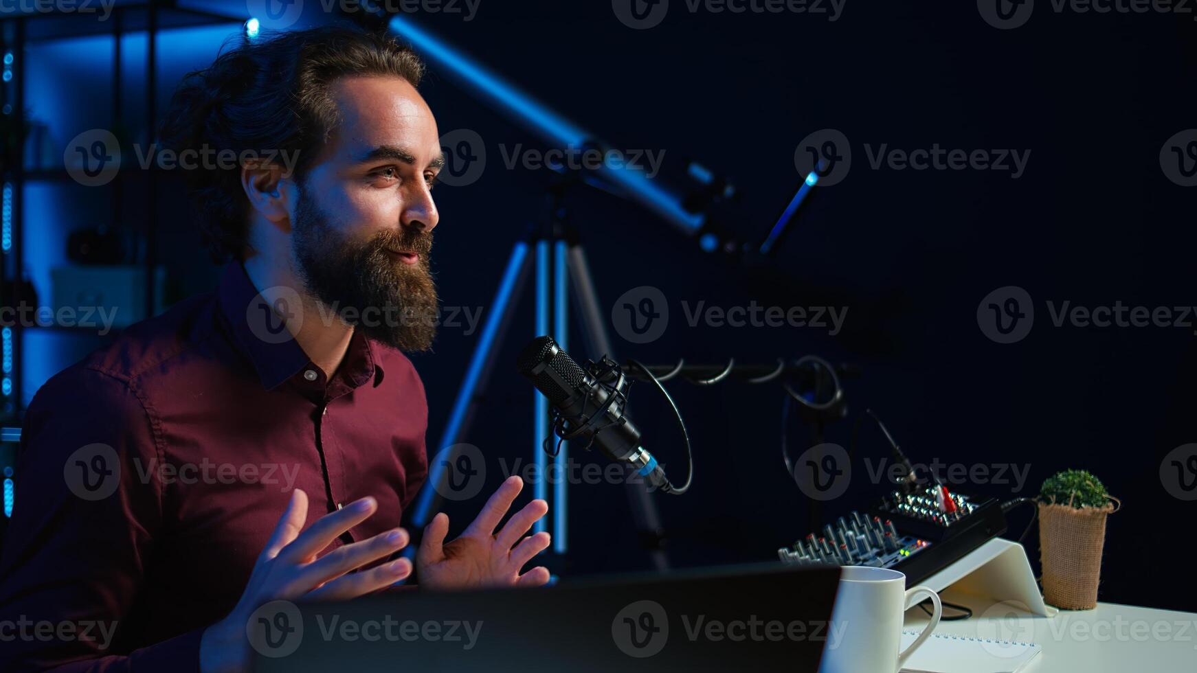 Upbeat content creator hosting online show in rgb lights studio, shooting vlog using professional microphone. Cheerful vlogger presenting informations during streaming service broadcast, camera B photo