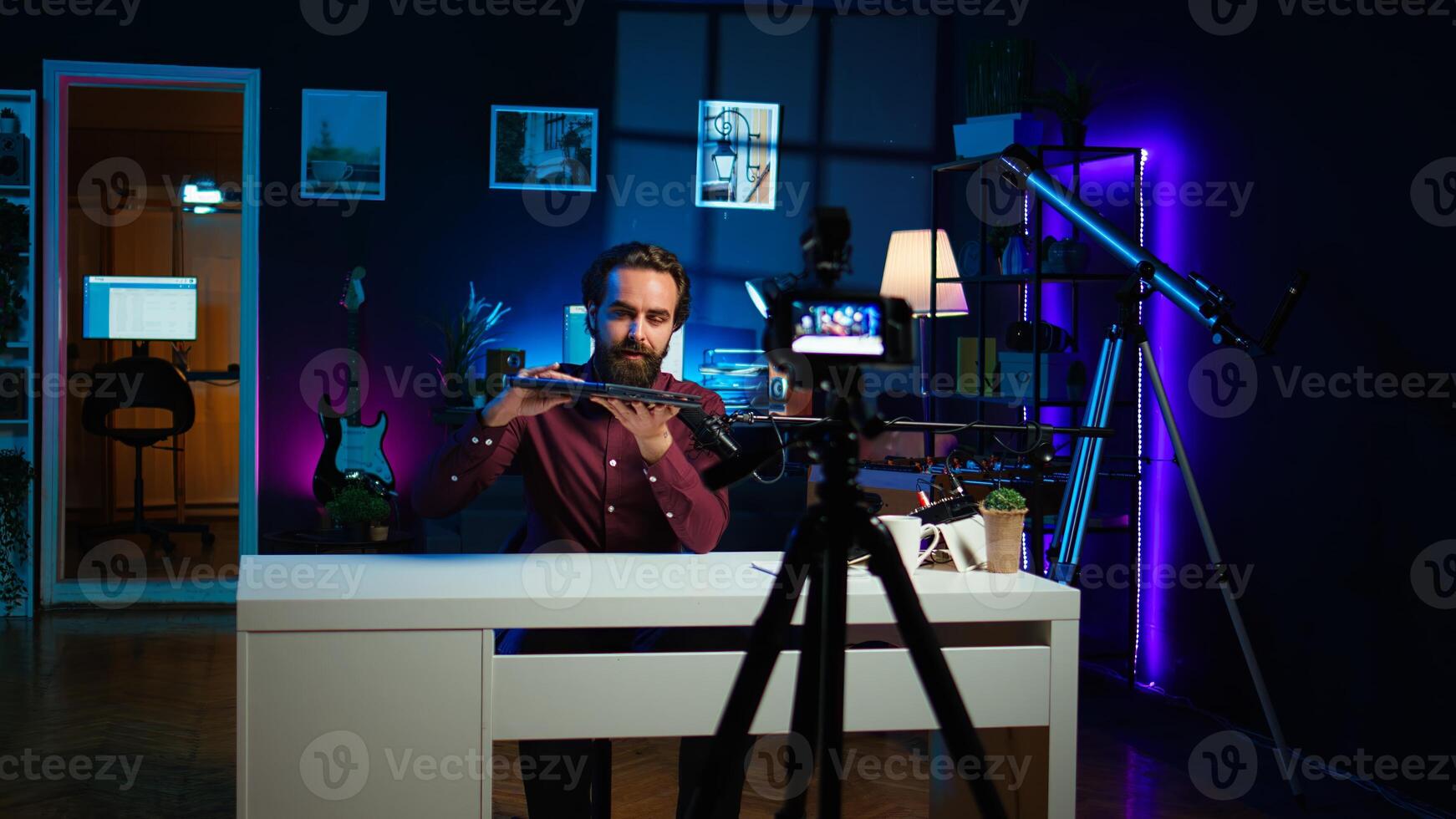 Smiling technology content creator filming review of newly launched gaming laptop, impressed by thinness. Internet star endorsing sponsor branded notebook to subscribers, camera B photo