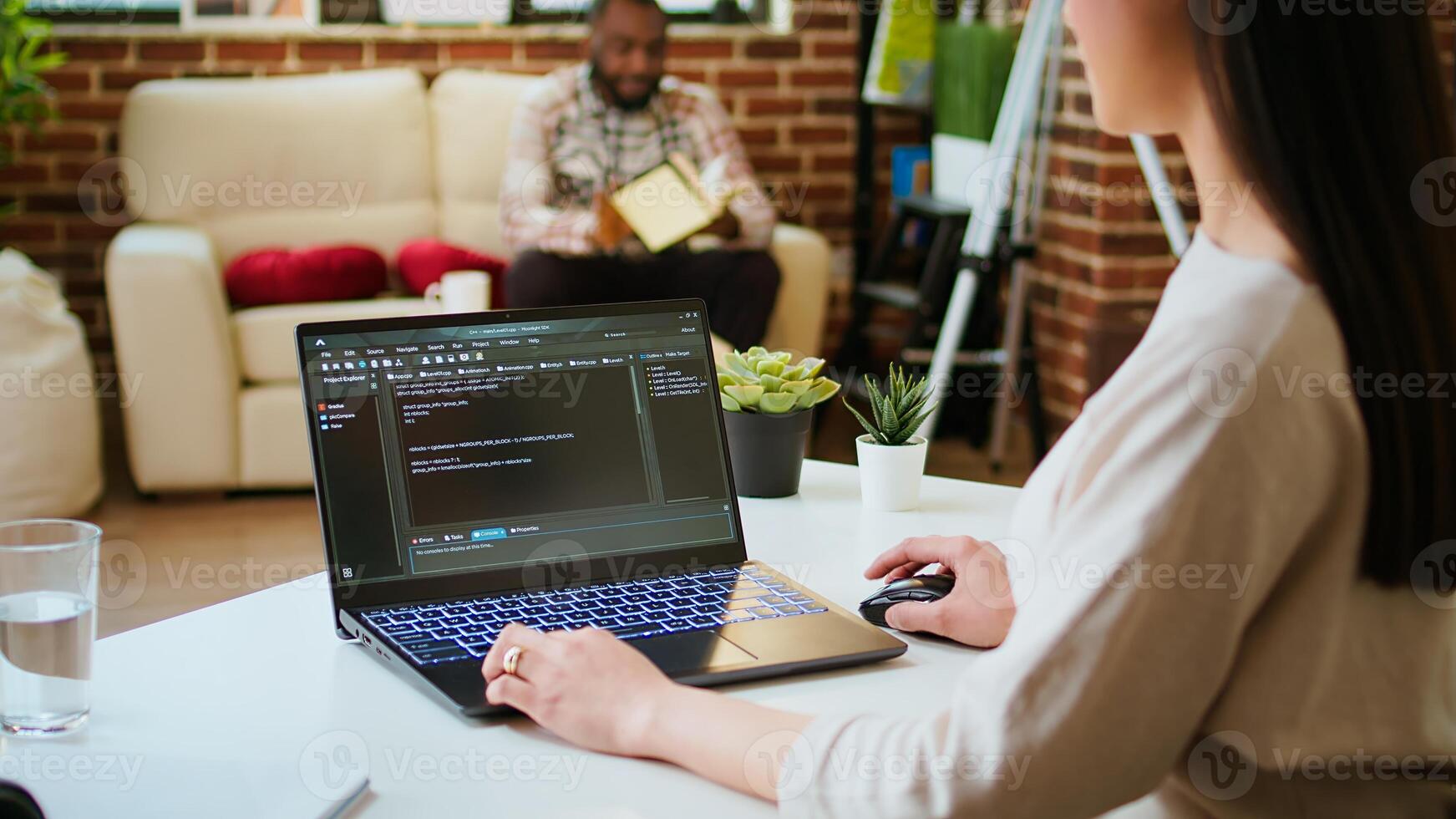 Asian female programmer works on coding software in a home office setup, typing code on a laptop. IT expert uses digital tools for multitasking, software development and app development. Camera A. photo