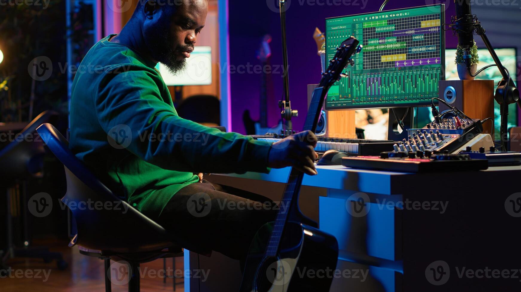 Creative songwriter singing a melody and playing guitar, signal processing technology with digital audio software. Artist producer creating music with acoustic instrument and console. Camera A. photo