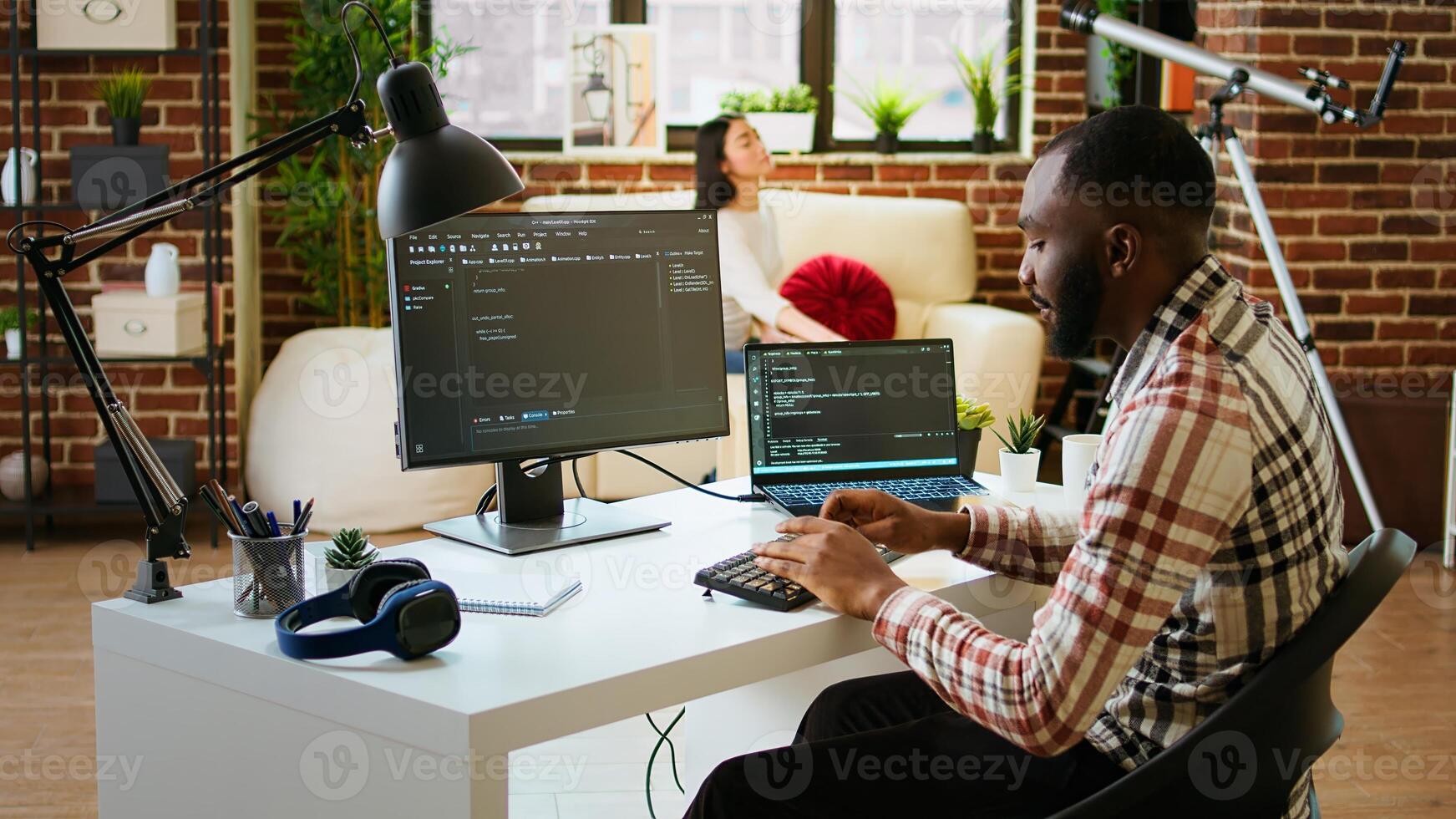 joven hombre visto programación software código en su ordenador portátil en un pulcro hogar oficina. espacio de trabajo con doble monitores ayuda con software ingeniería, web desarrollo y codificación productividad. cámara una. foto