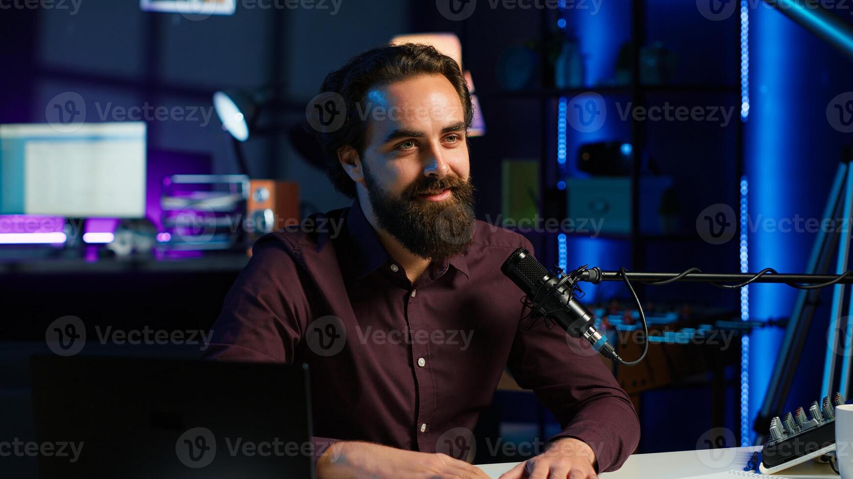Content creator talking about himself while recording with production gear in home studio interior illuminated with RGB lights at night. Entertainer talking in professional microphone, camera A photo