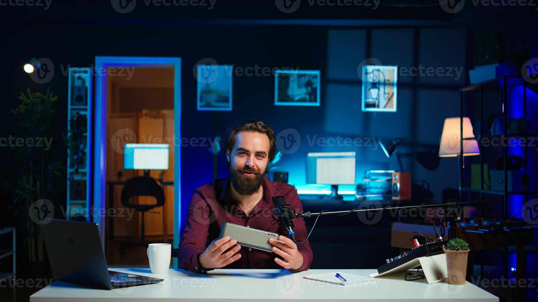 Smiling media star doing technology review of wireless portable speaker for online platforms channel. Cheerful influencer presenting music playing device to his audience, camera B photo
