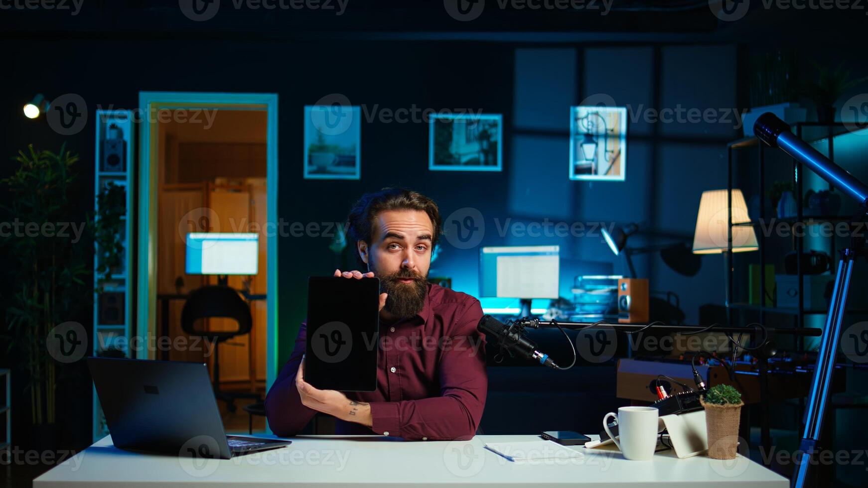 Entertaining man in studio films tablet review for tech enthusiasts. Viral media star hosts technology internet show, unboxing digital portable device, feeling impressed by thinness, camera B photo
