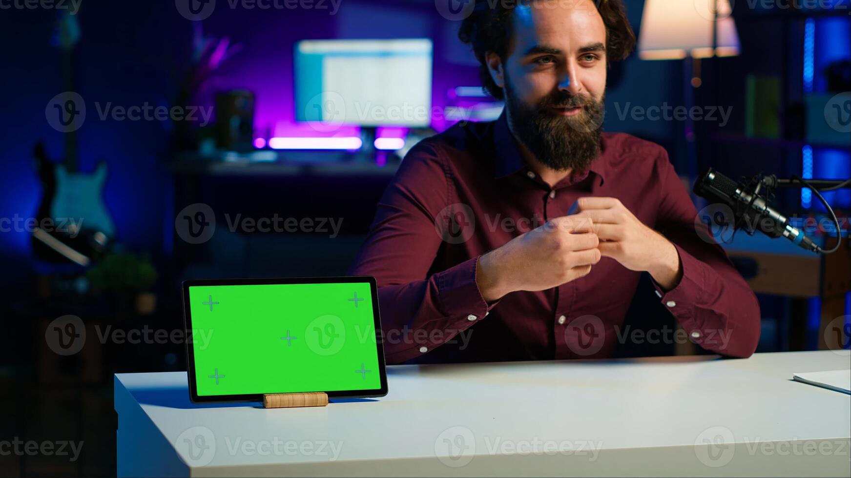 Tech specialist presenting mockup tablet to interested viewers, filming with professional mic. Man reviewing green screen digital device, recording with specialized equipment, camera A photo