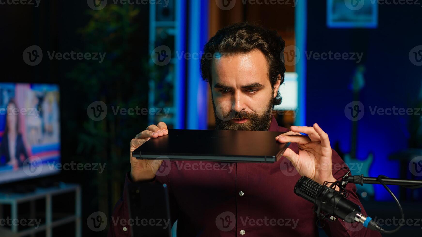 Tech expert assessing laptop performance, talking about components used inside, filming with smartphone. Entertainer reviewing notebook on technology internet channel, recording with phone, camera A photo