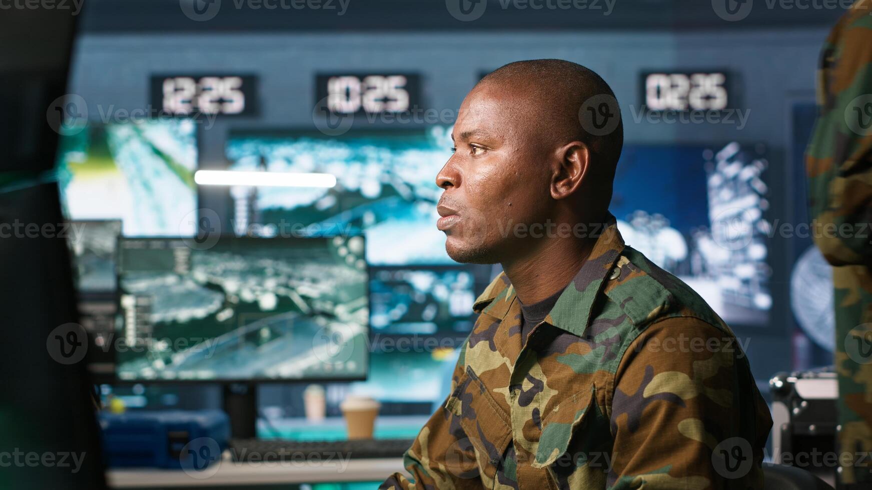 Intelligence operative in military base doing surveillance with digital radar equipment, operating missile systems. African american man monitoring army HQ CCTV for any unauthorized activity, camera A photo