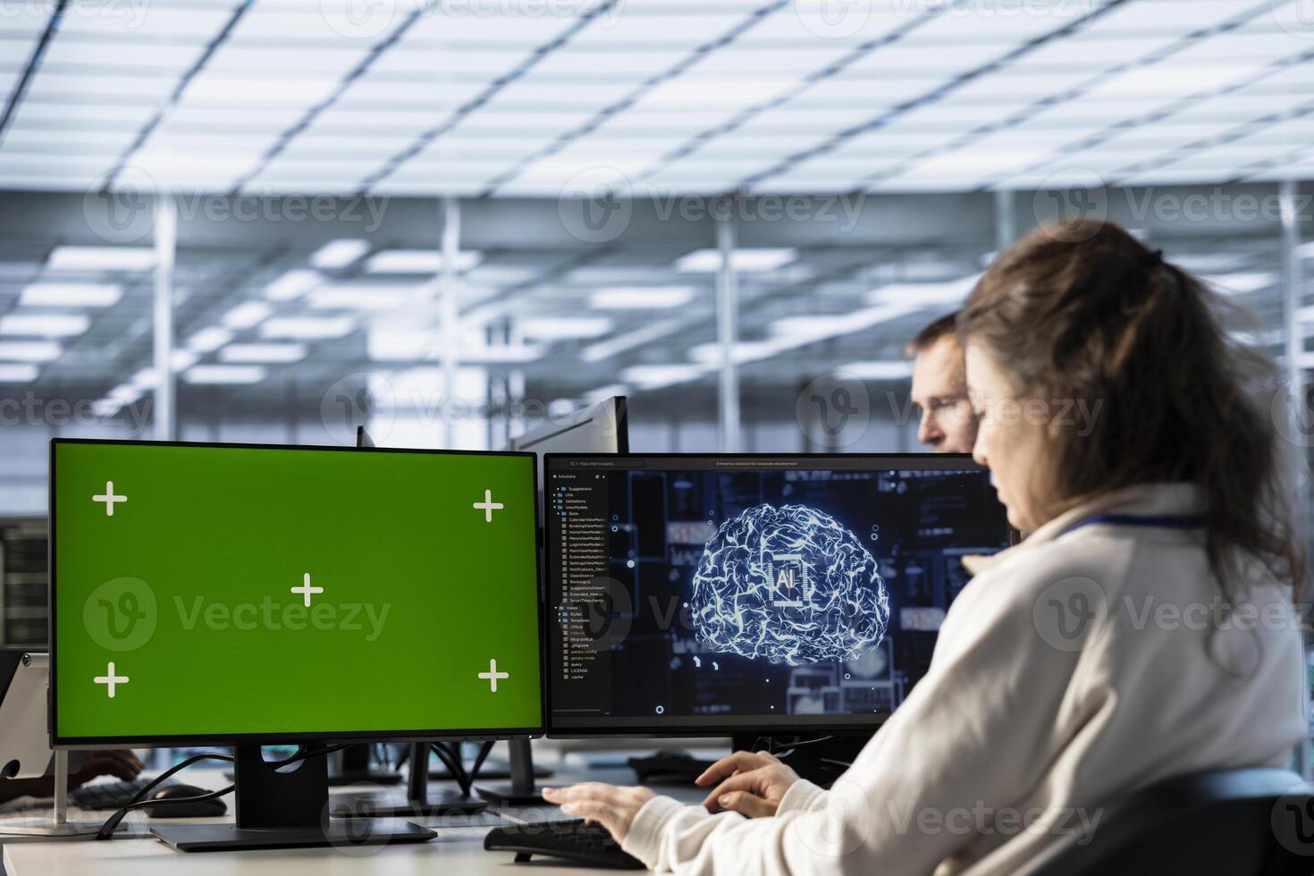 Woman in AI data center coding on green screen computers, upgrading equipment. IT engineers at PC desk overseeing artificial intelligence server clusters using mockup monitor photo