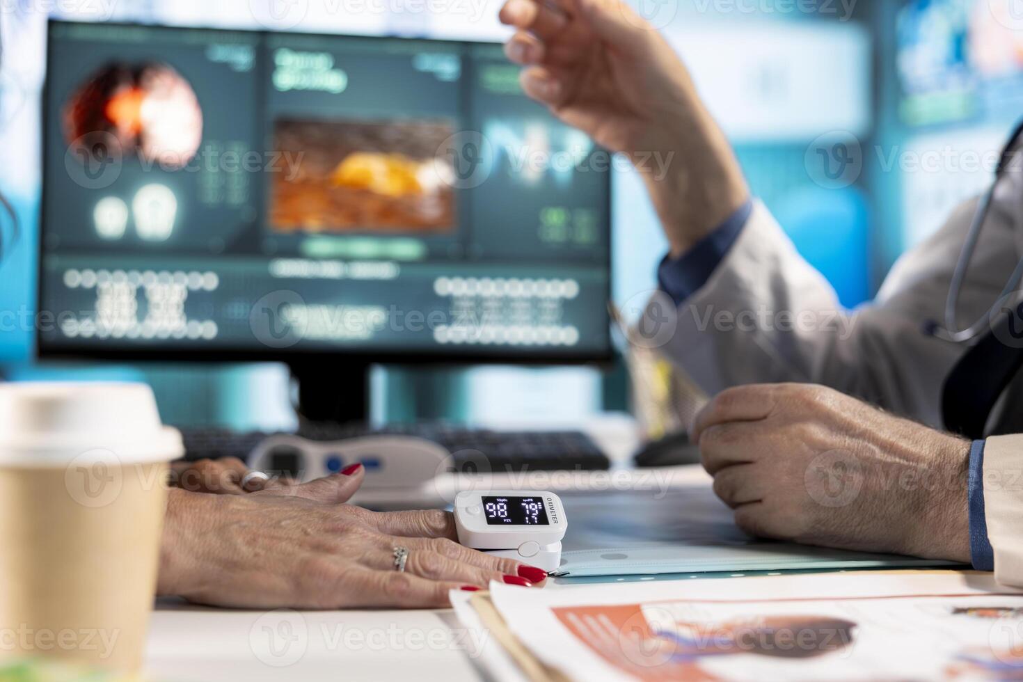 Medical specialist takes the oxygen saturation measurement at consultation, using oximeter on finger and consulting senior patient at facility. Physician checking pulse rate and vital signs. photo
