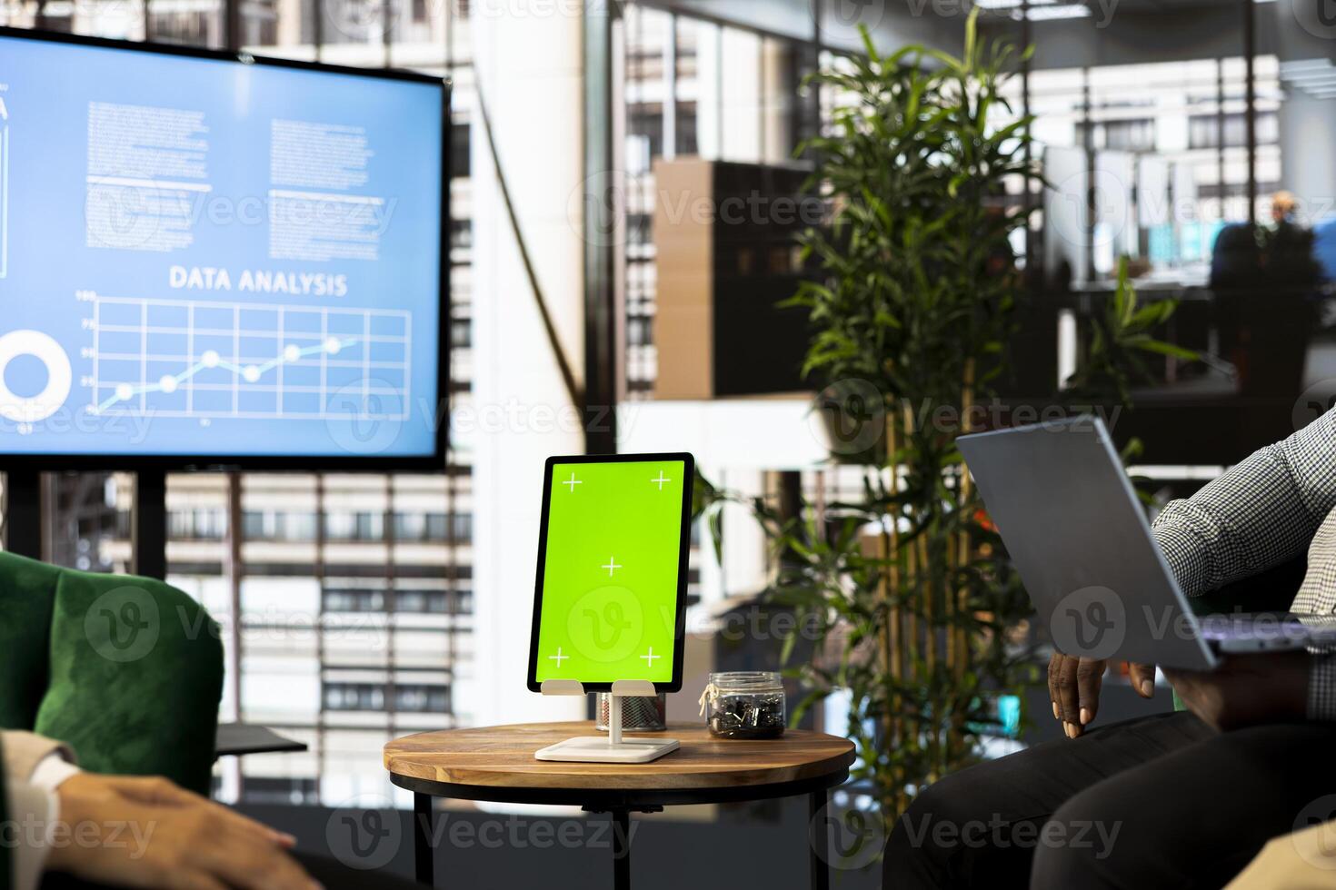 Mockup tablet next to team of office clerks looking over revenue figures in office. Staff members comparing company statistical numbers on green screen device, working hard to finish before deadline photo