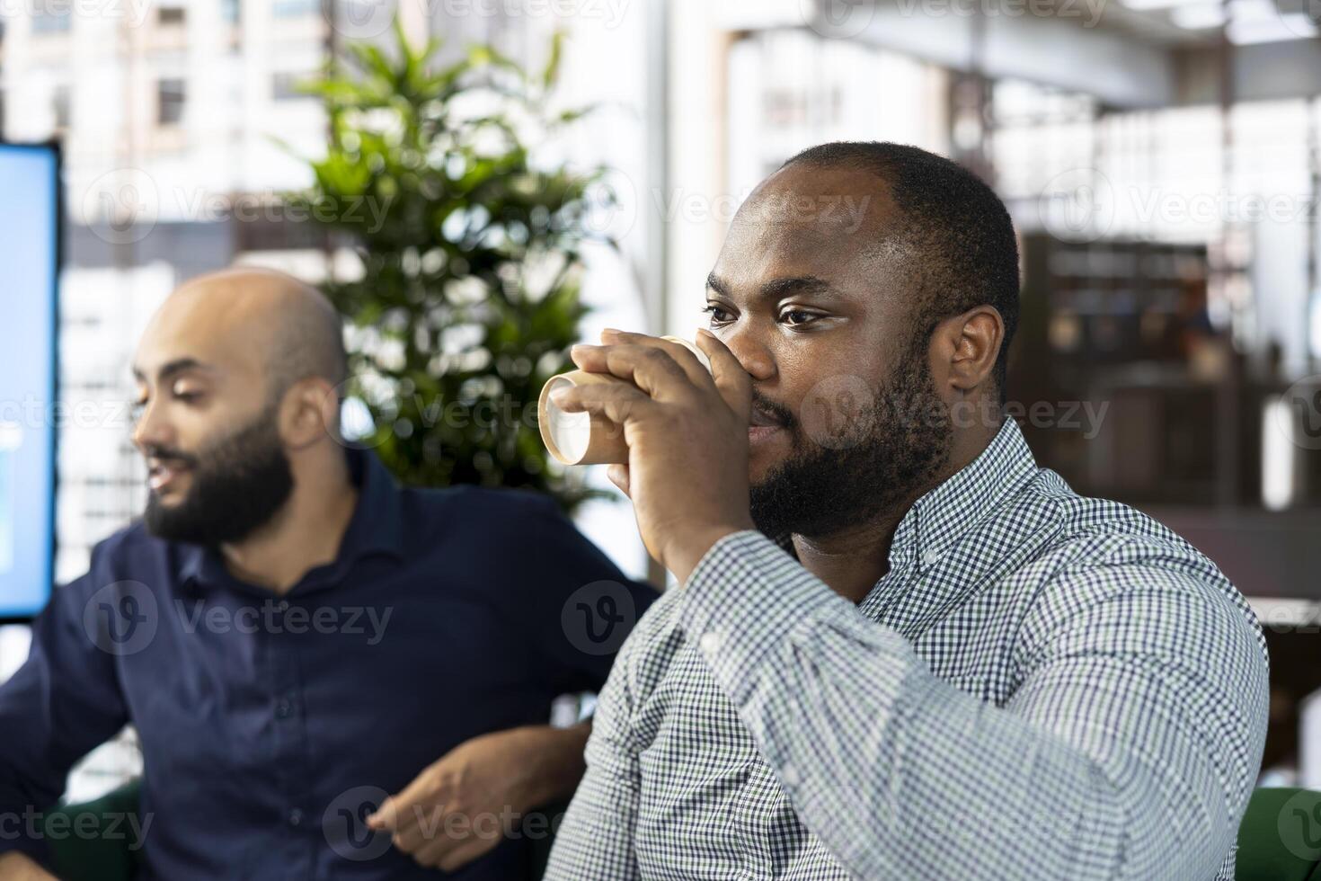Man in startup company enjoying cup of coffee, looking at financial business documents. Worker in office drinking caffeinated beverage to gain energy, trying to finish tedious paperwork photo