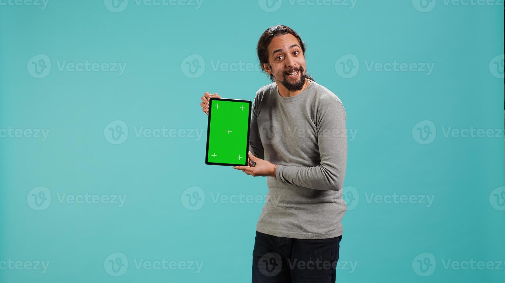 Happy man holding green screen tablet, doing recommendation. Cheerful person presenting mockup device, showing positive feedback, isolated over studio background, camera A photo
