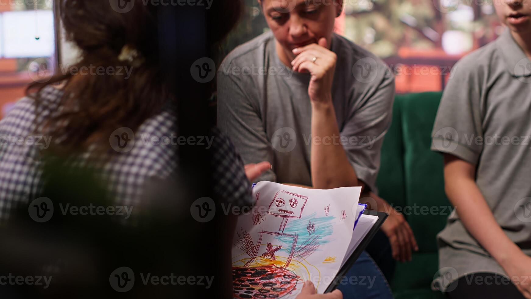 Expert shows disturbing gory drawings to mother of a disconnected girl who struggles to focus, depersonalization concept. Adolescent with derealization and dissociation issues. Camera A. photo