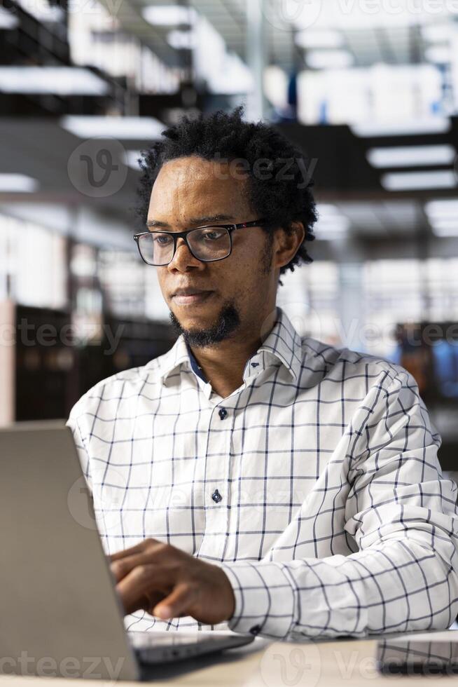 Confident businessman at his office desk working on report writing, financial planning and deadline management. Expert specialist reviewing objectives and goals to ensure success. photo