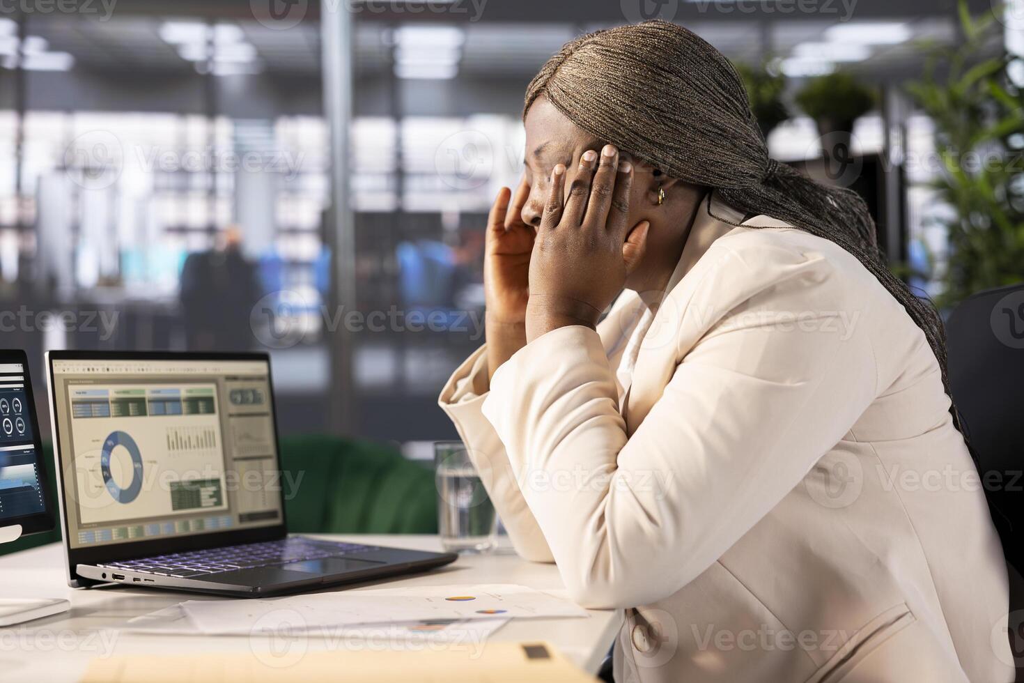 Overworked woman having migraine symptoms while looking over statistics charts on laptop, researching data. Tired worker in pain, feeling discomfort while doing research for marketing project photo