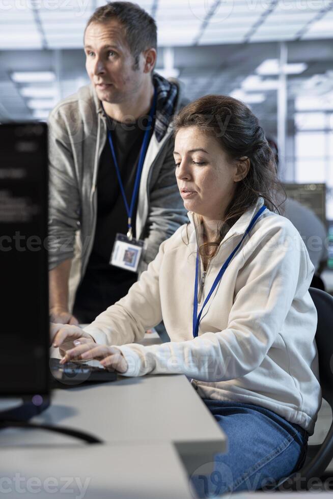 Supervisor checking project progress of technician programming in data center used for machine learning training. Team leader overseeing employee coding on computer in server room photo