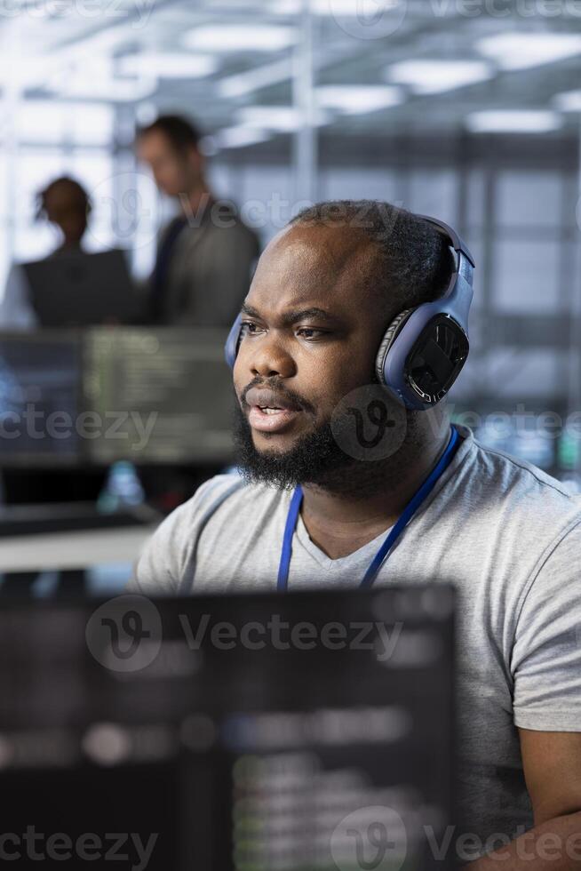 Engineer in data center listening music, optimizing IT infrastructure using network management skills. Server room expert wearing headphones upgrading gear, reducing operational costs photo