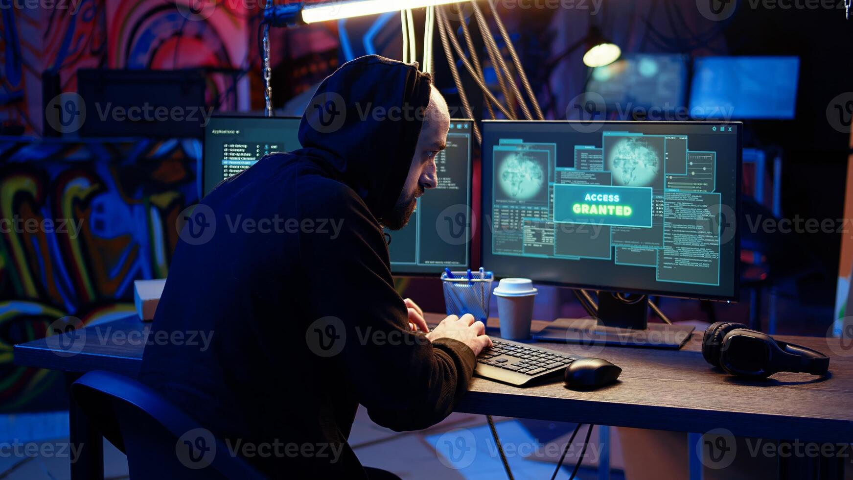 Jolly hacker in graffiti painted hideout excited after managing to steal valuable data, using phishing technique that tricks users into revealing passwords, getting access granted, zoom in shot photo