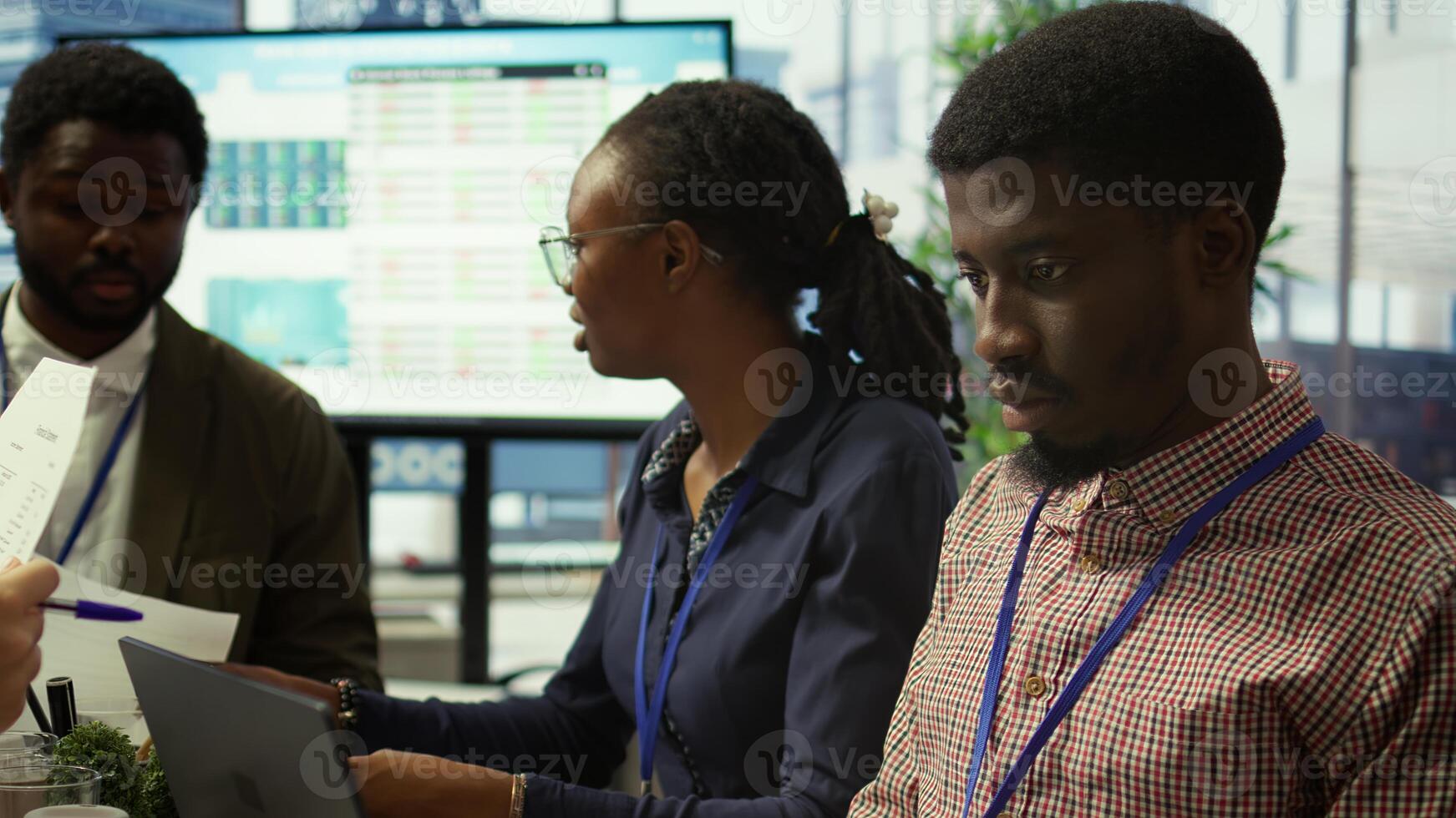 Team of business associates reviewing statistics and infographics on a tablet, working to gather insight for enterprise development. Employees discussing legal changes at a meeting. Camera B. photo