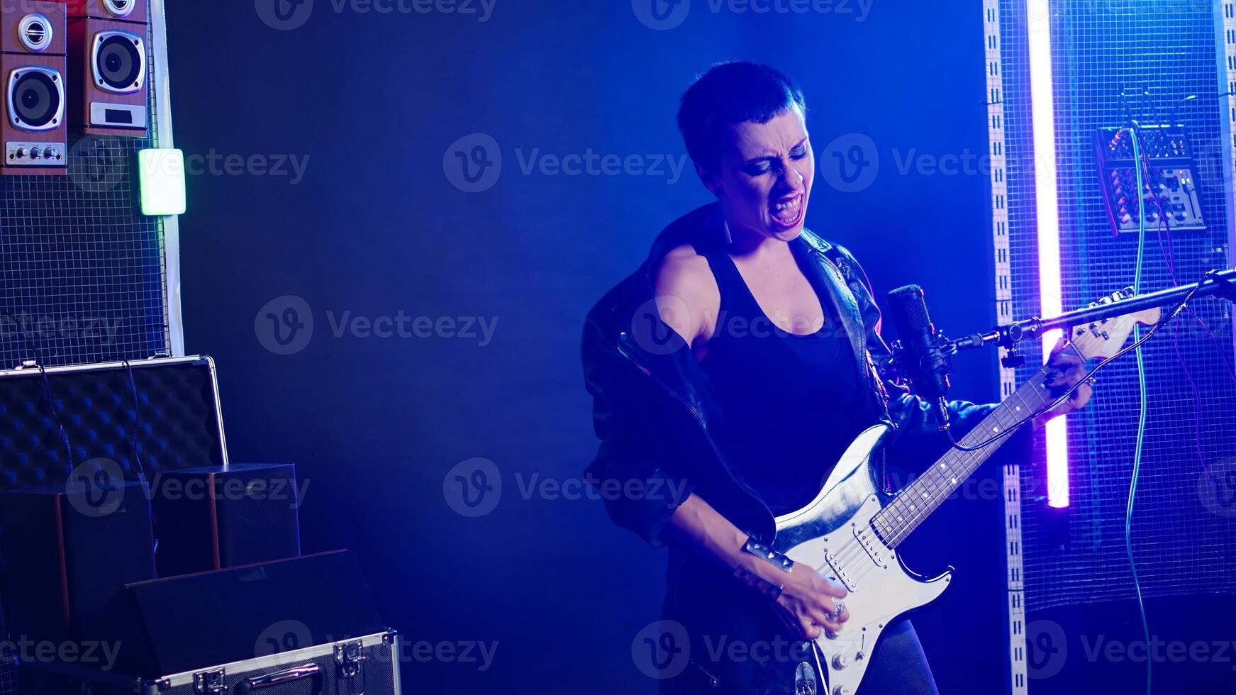 Talented female guitarist delivers a powerful music performance in a dark urban studio. Musical artist with grunge style and cool energy making her a superstar performer. Heavy metal. Camera A. photo