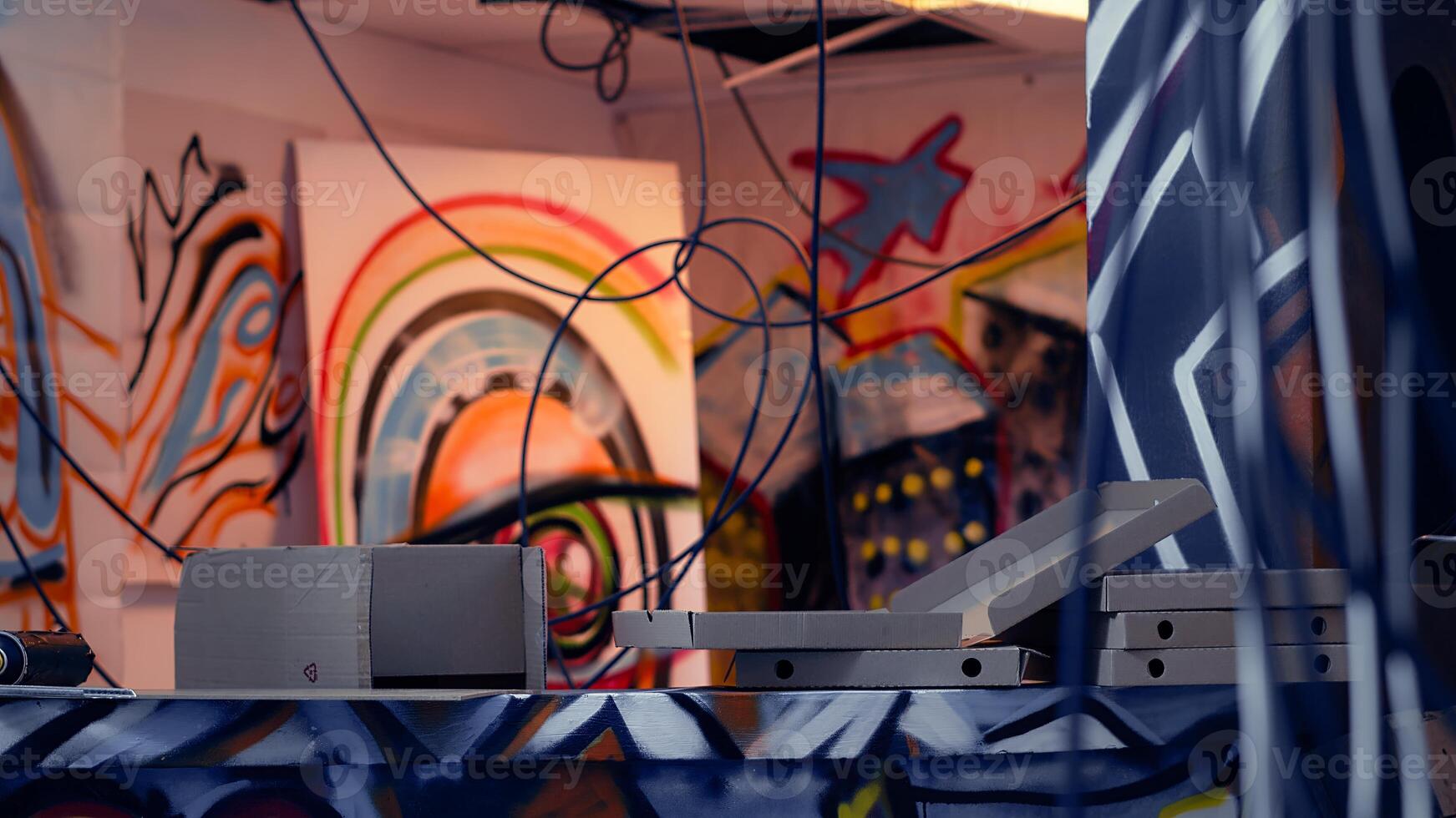 Close up of pizza boxes leftover by guerilla artists in building with graffiti drawings sprayed on walls. Thrown objects in desolate defaced location used by teens to do art, concept of urban culture photo