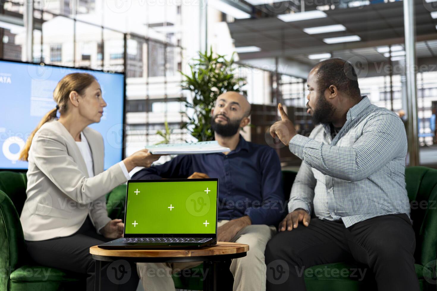 Multiethnic colleague using green screen laptop, doing briefing meeting to share new ideas for profit growth. Diverse team of employees in office talking with director, using chroma key notebook photo