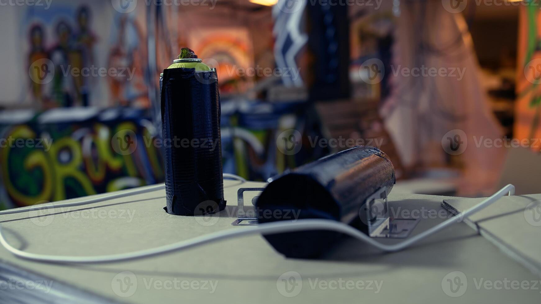 Close up of spray cans in empty industrial warehouse with graffiti drawings on walls. Focus on paint cans with underground location used as crime haven by delinquents in blurry background photo