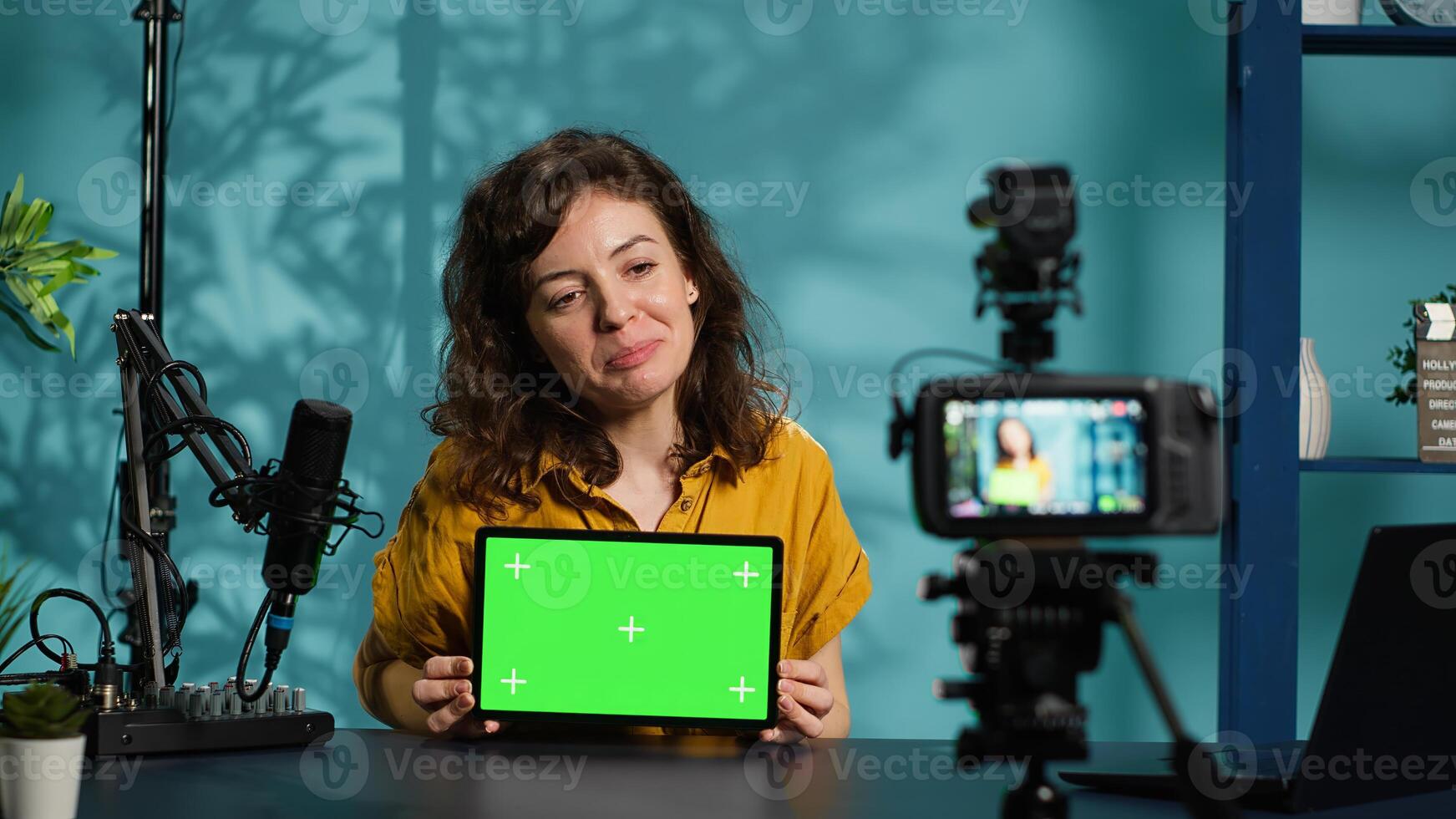 Media star sponsored by brand to do mockup tablet unboxing, recording with advanced gear. Woman does influencer marketing, presenting green screen device, filming with professional camera, camera A photo