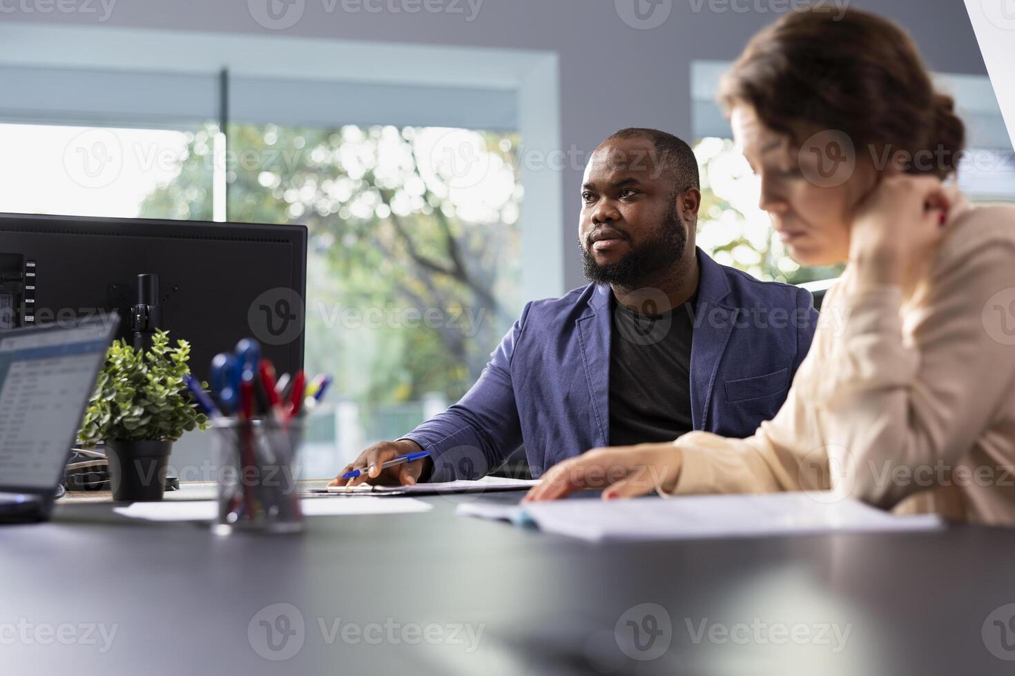 Car dealership sales executive preparing purchase paperwork and documentation after agreeing terms with customer during test drive. Showroom worker giving sale contract for husband and wife to sign photo