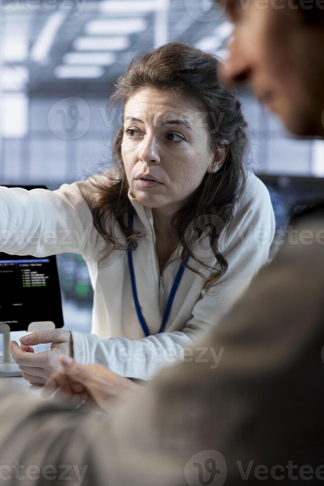 Teamworking colleagues in data center coordinating deployment of server architecture, improving data processing speed. Coworkers doing brainstorming in server farm configuring and testing equipment photo