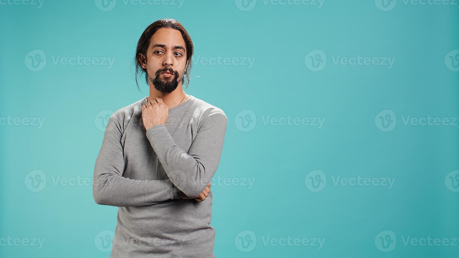 Portrait of man scratching neck with fingers, listening for unfamiliar sound, concentrating on finding source. Person tilting head, focusing on identifying noise, studio background, camera B photo