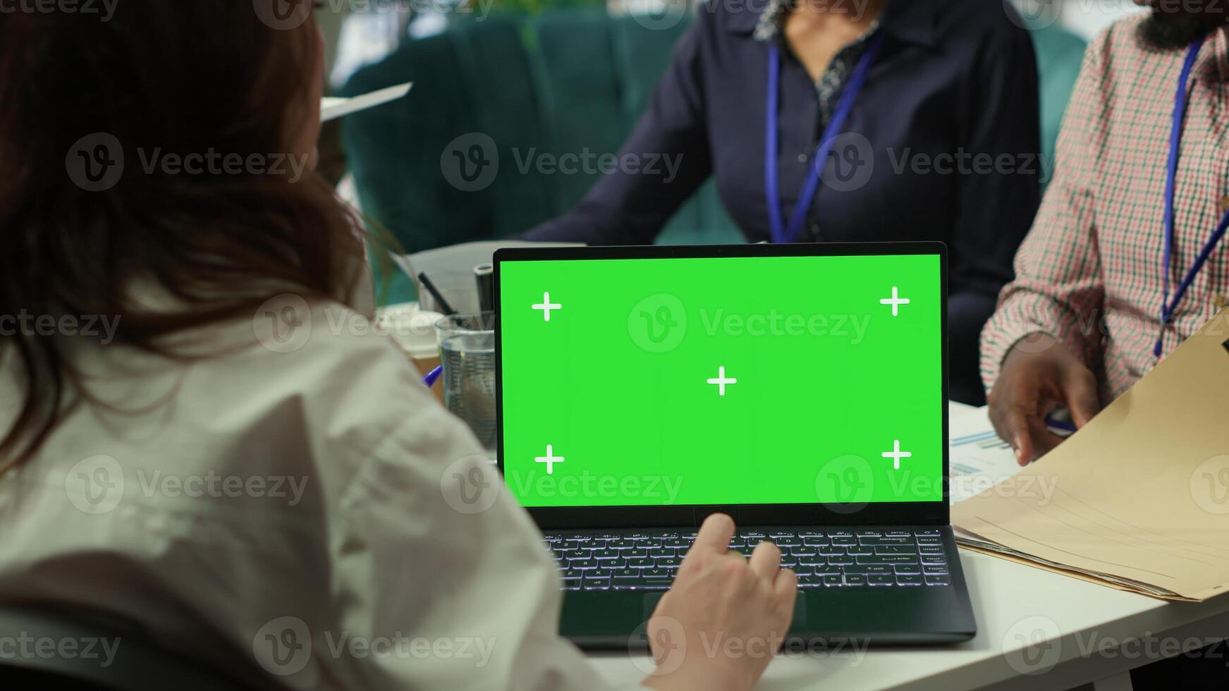 Diverse team of business associates looking at mockup chroma key screen during executive board meeting, utilizing smart technology. Enterprise staff develop effective business strategies. Camera A. photo