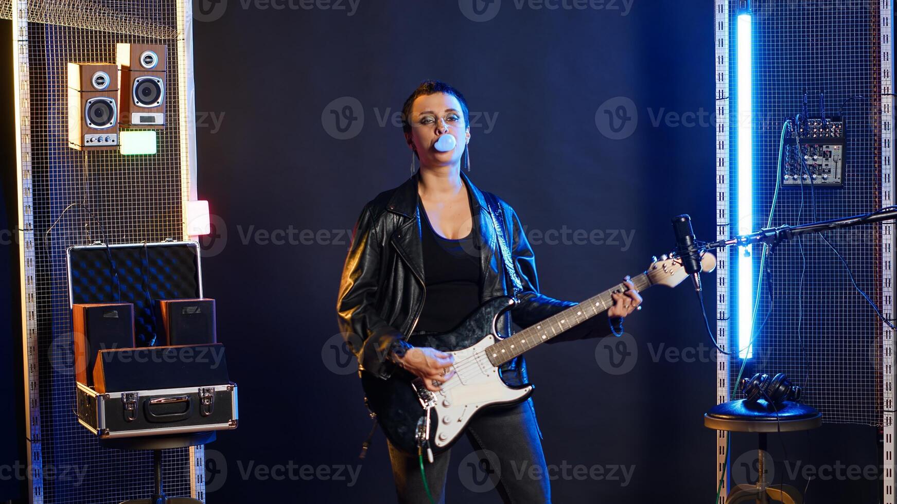 Iconic grunge rocker chewing gum and making bubbles during live performance, acting tough and fierce with an edgy attitude. Woman superstar blowing bubble gum balloons. Camera B. photo