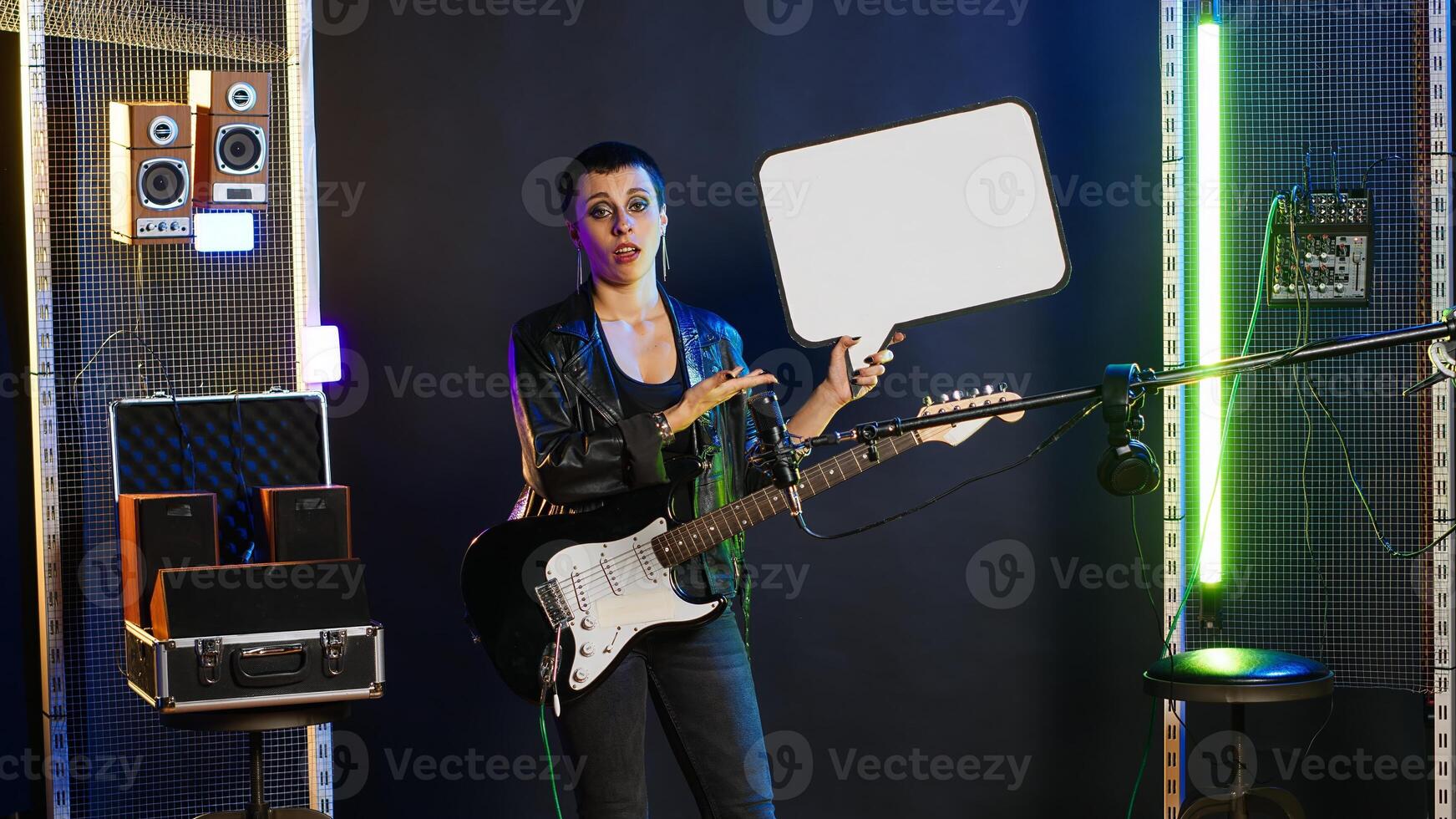 Female rock star performer showing the empty cardboard speech bubble, presenting her rebellious grunge attitude as an artist. Woman musician does a commercial ad with billboard. Camera B. photo