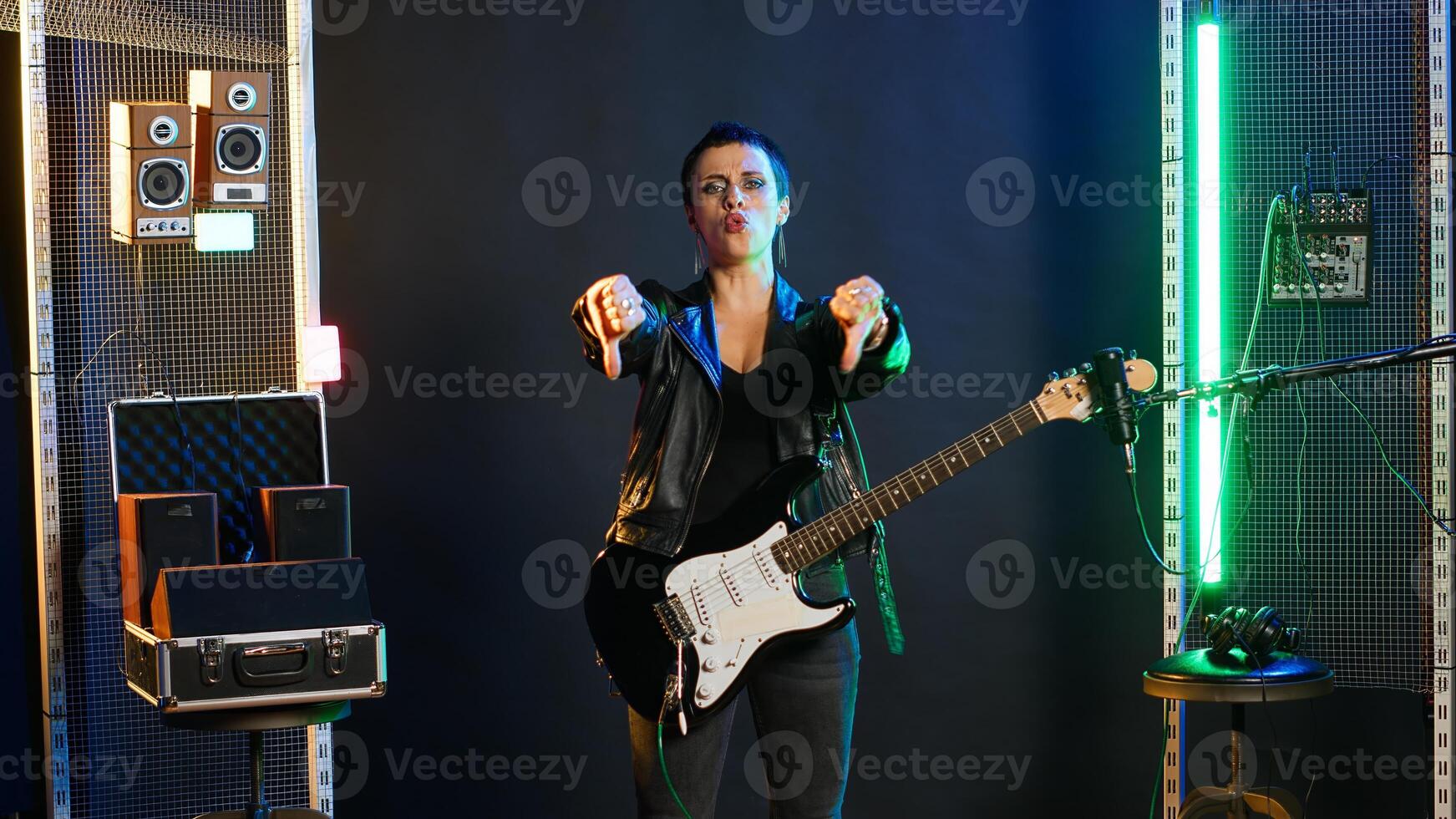 Displeased woman giving a dislike while she performs live in concert, expressing her disagreement with a thumbs down in studio. Dissatisfied female rocker with a cool edgy vibe. Camera B. photo