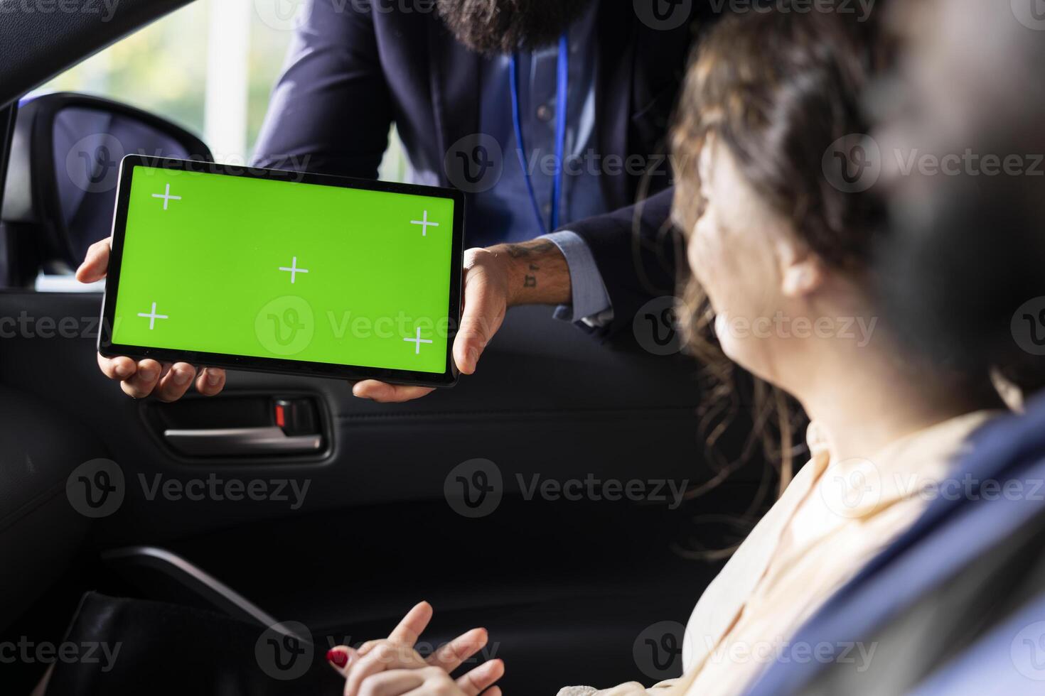 Car salesman showing product offerings on green screen tablet to woman, making recommendations. Showroom agent presents financing options to customer during test drive using chroma key device photo
