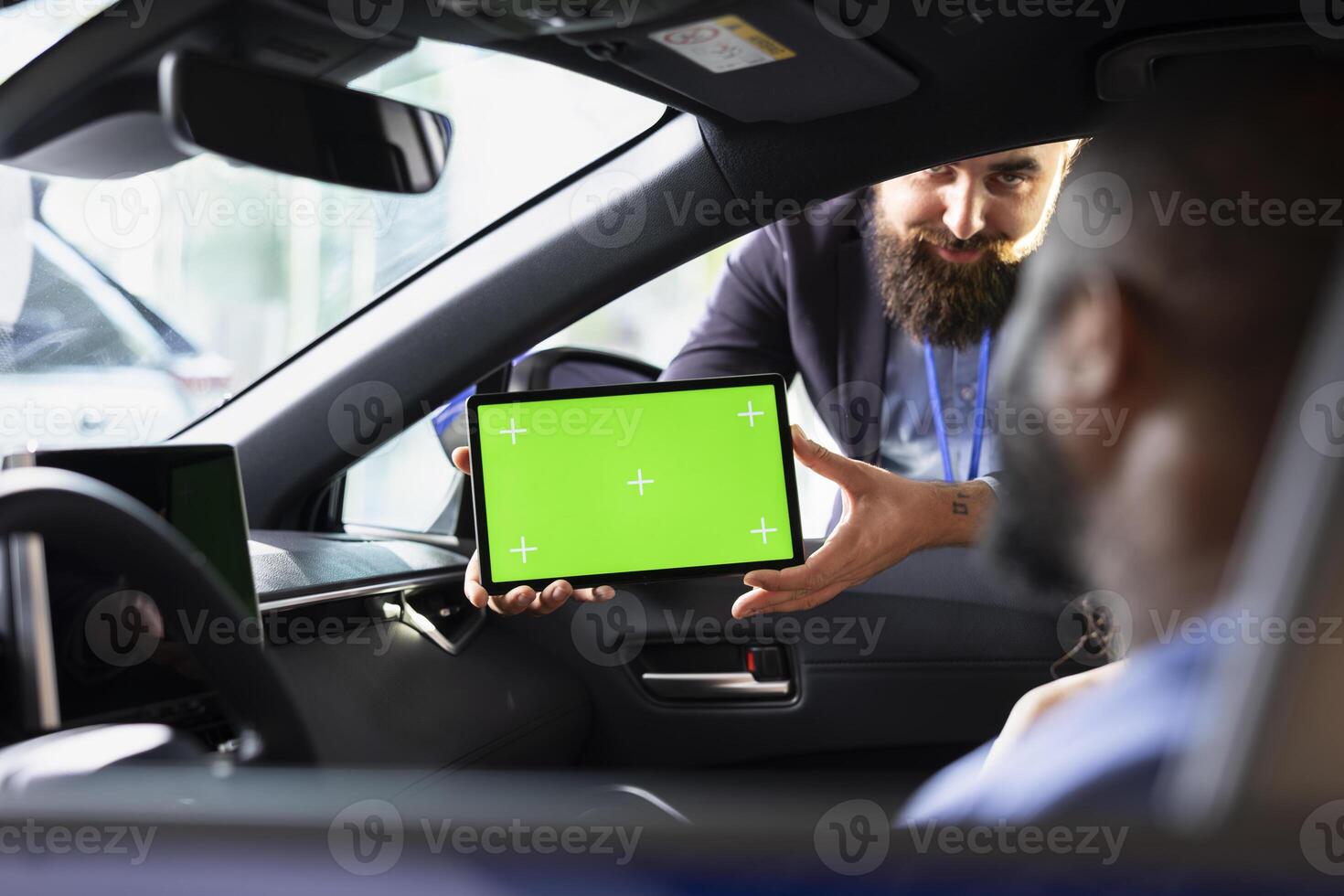 Smiling salesman using green screen tablet to present car addons options to clients, after finishing test drive. Showroom agent mockup device to husband and wife driving vehicle photo