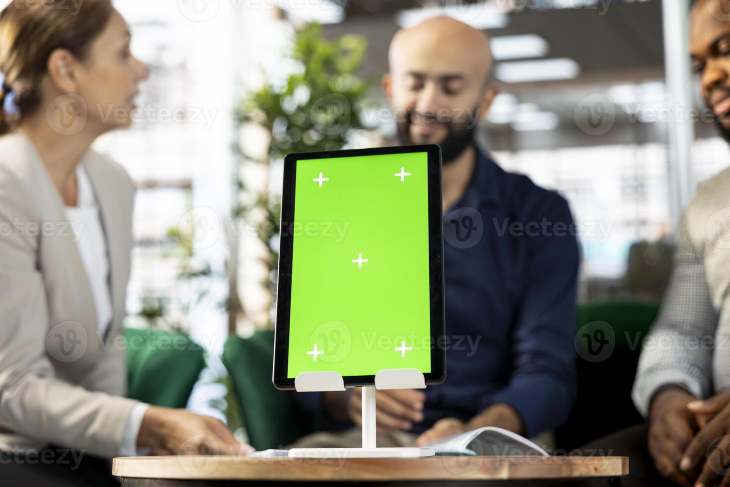 Focus on isolated screen tablet in front of businesspeople talking in startup company, looking at financial business documents. Close up of mockup device used by office clerks in blurry background photo