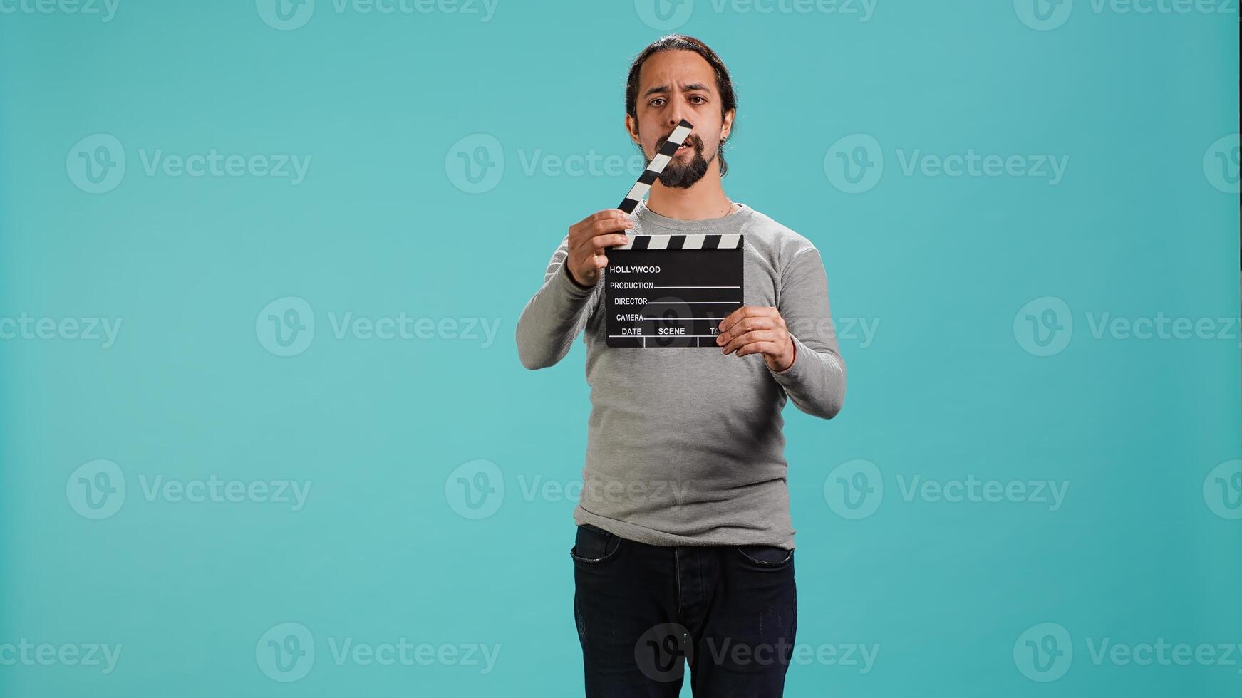 Movie director using clapper to signal actors beginning of scene recording, studio background. Film producer on set filming production, using clapperboard, camera A photo