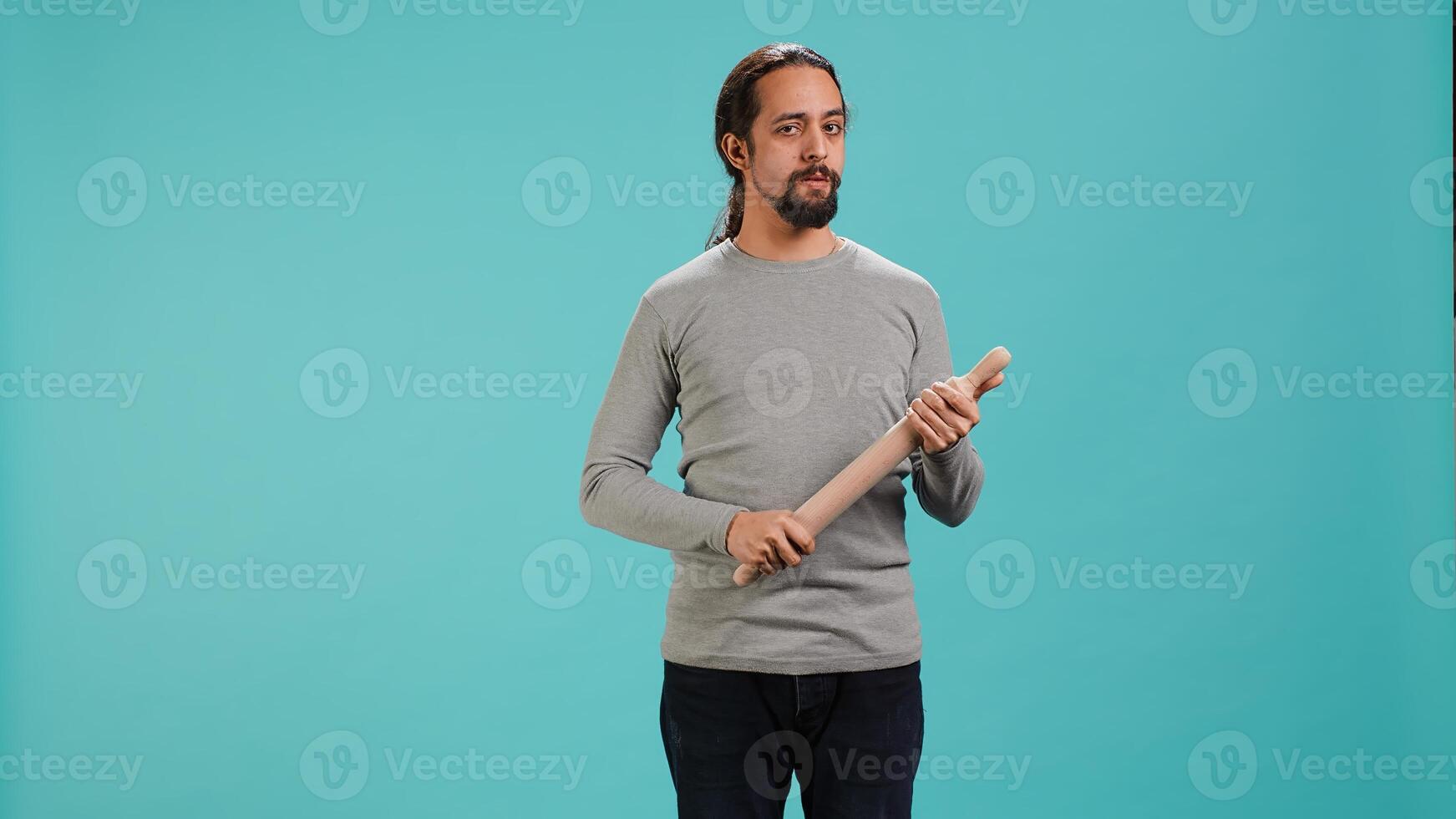 Portrait of menacing man threating to hit enemy during fight. Wrathful Arab person full of rage intimidating mate, holding weapon, isolated over studio background, camera A photo