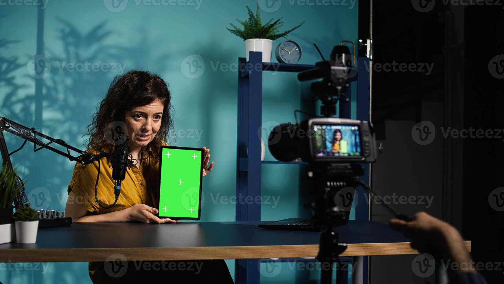 Woman holding green screen tablet, talking about specifications, filming with professional camera. Internet show host presenting chroma key device features, recording with filming gear, camera B photo