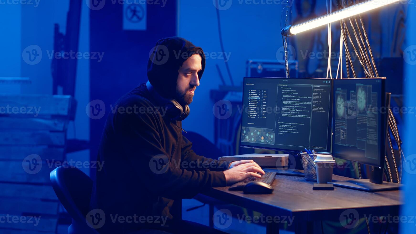 Hooded hacker creating pirating crack for software and game releases in bunker. Rogue programmer getting past anti tamper measures implemented by companies to protect their products, camera B photo