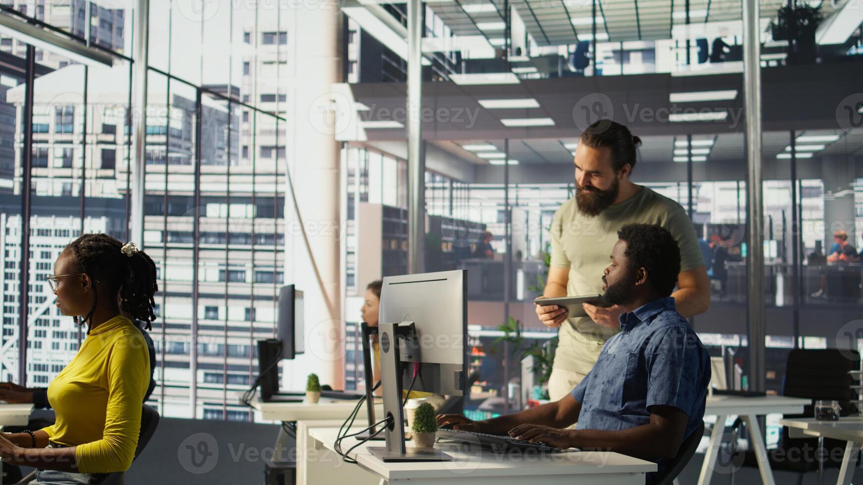 Manager coming to check on IT employee at office desk testing and deploying programs and systems. Team leader supervising developer writing code on computer in workspace, camera B photo