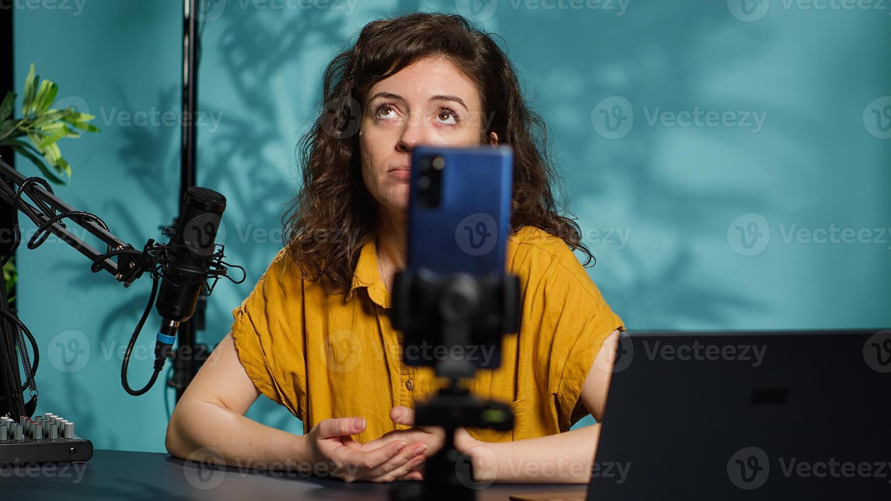 Content creator using smartphone on phone holder to shoot intro for vlog channel on online platforms. Internet star warmly welcoming dedicated fanbase, filming with cellphone, camera A photo