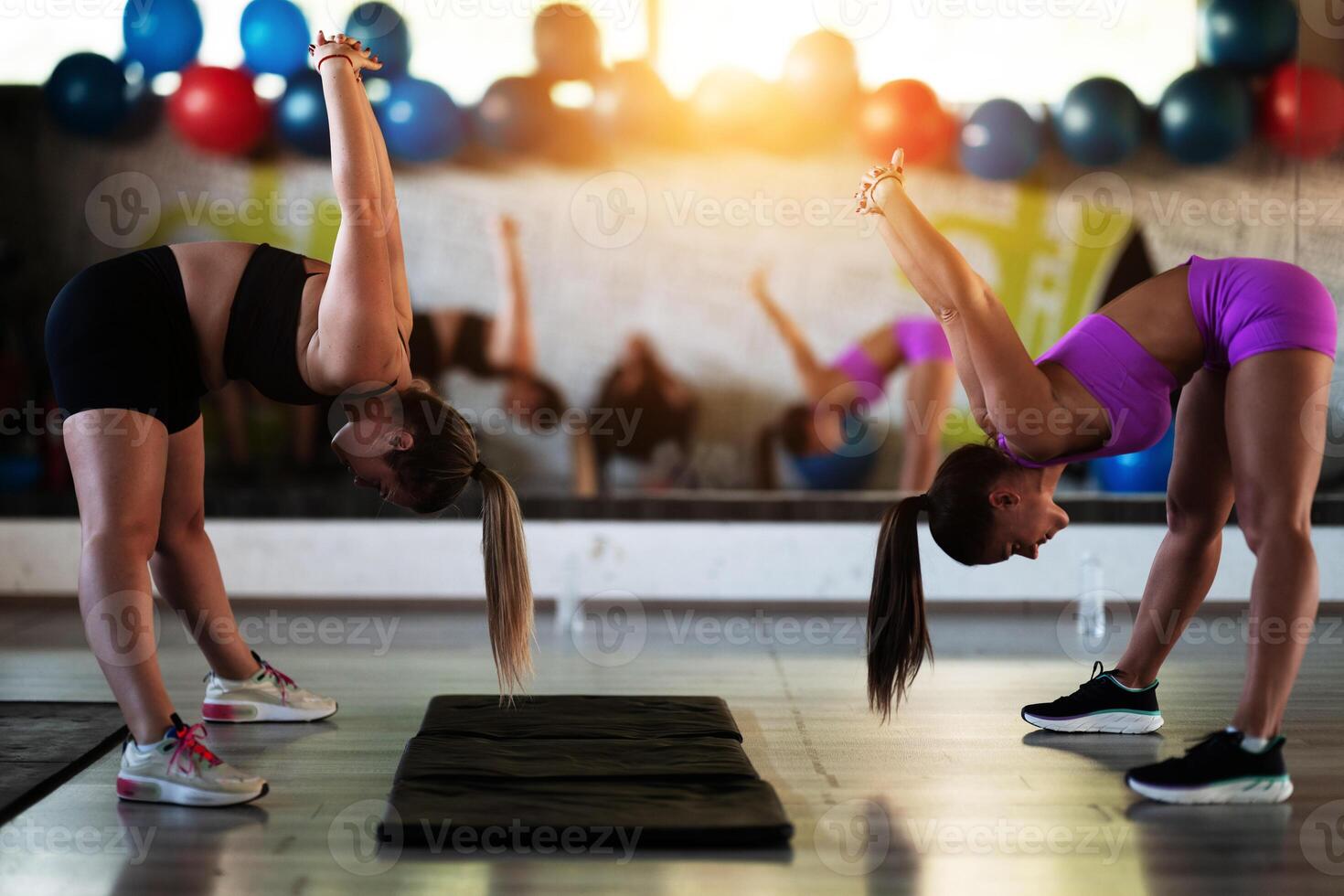 Two fitness women stretch together in the gym, supporting each other in their journey towards flexibility and wellness. photo