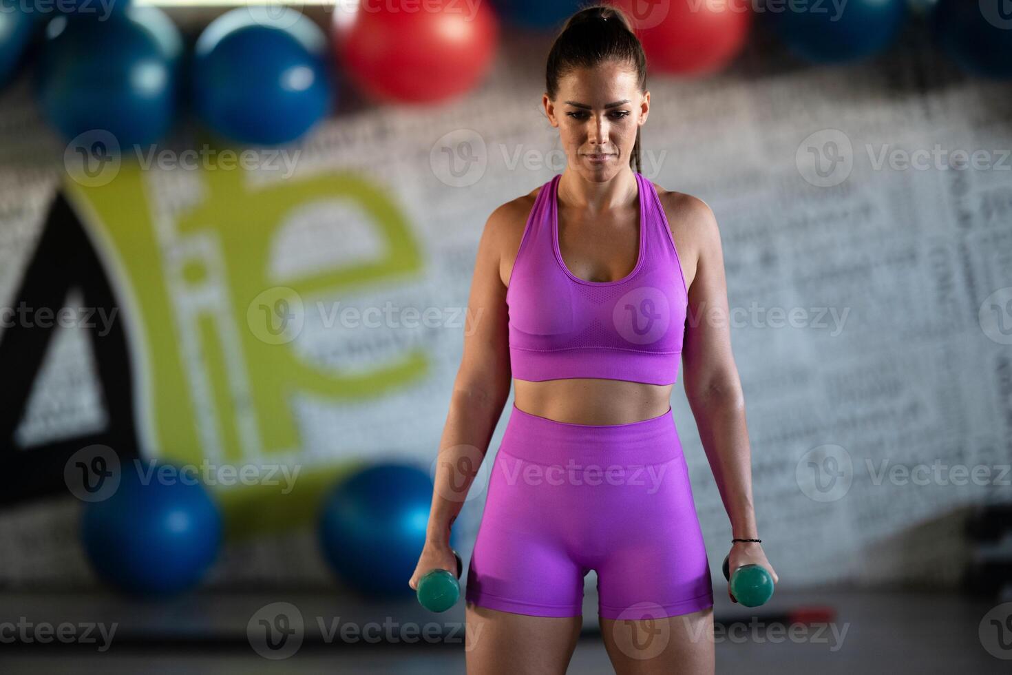 A focused and determined woman performs a strength building dumbbell workout at the gym, showcasing her athletic physique and dedication to fitness. photo