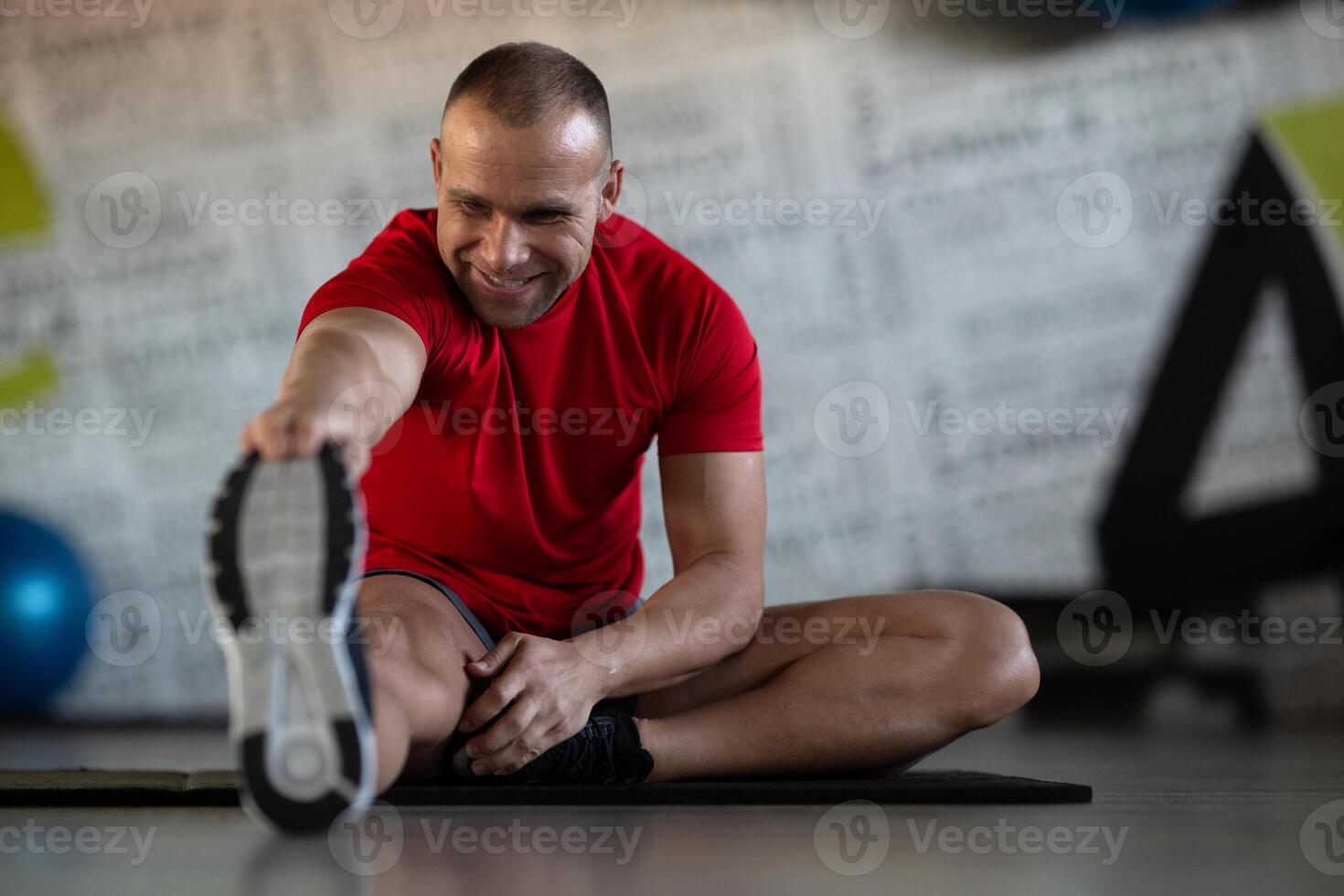 A fitness man stretches in the gym after an intense workout, focusing on recovery and flexibility. photo