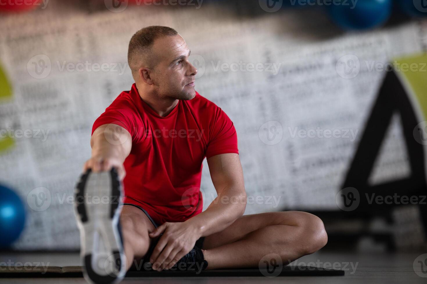 A fitness man stretches in the gym after an intense workout, focusing on recovery and flexibility. photo